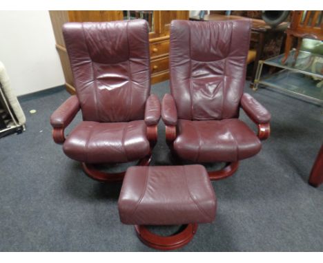 A pair of Himolla wood framed manual reclining swivel armchairs upholstered in a Burgundy leather with matching foot stool. 