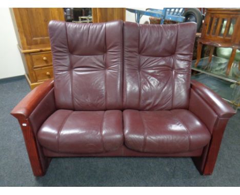 A Himolla manual reclining two-seater settee upholstered in a Burgundy leather. 