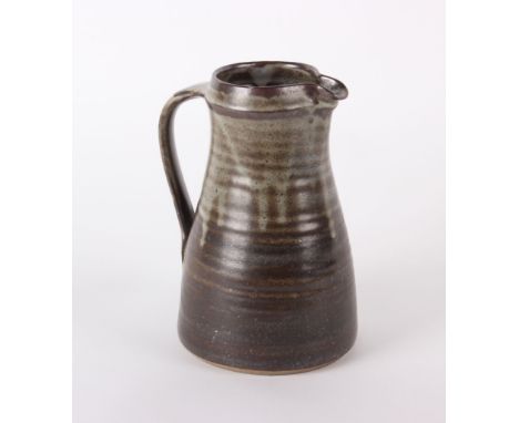 A stoneware jug in the style of Bernard Leach of ribbed tapering form with an impressed mark (H: 24cm)