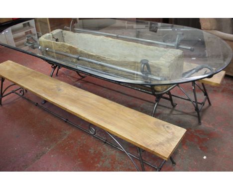 A modern designer dining table set with oval plate glass top on metal stand incorporating a weathered wood planter/trough tog