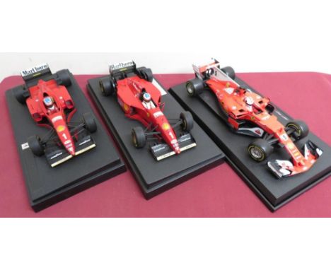 Burago 1:18 scale model of a Ferrari driven by Sebastian Vettel, and two Ferrari's driven by Michael Schumacher, all on plint