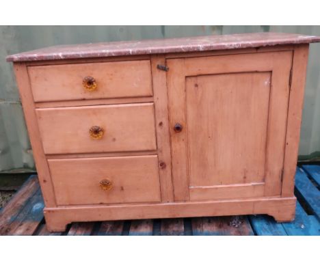 Victorian waxed pine marble top wash stand with single panel cupboard door flanked by three drawers with amber handles, on br