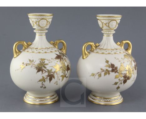 A pair of Royal Worcester ivory ground twin handled vases, date code for 1887, each gilt decorated with flowers and foliage, 