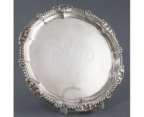 A George III silver circular salver by Paul Storr, with shell and gadrooned border and engraved armorial, on foliate scroll f