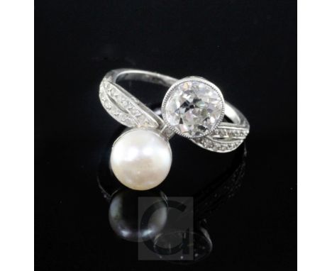 A platinum, cultured pearl and diamond set crossover ring with diamond set shoulders, the large diamond weighing approximatel