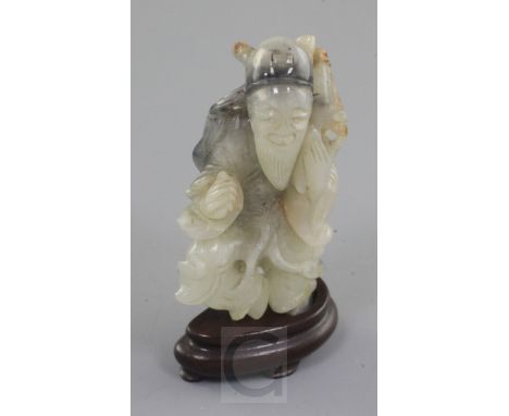 A Chinese white and black jade figure of an old man, 18th / 19th century, holding a sprig in his left hand, 7.3cm, wood stand