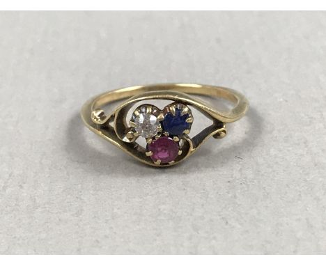 A vintage three-stone dress ring, comprising round-cut diamond, ruby and sapphires, twist-set in a scrolling yellow-metal sha