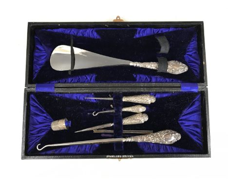 An Edwardian cased silver-handled button hook and shoe horn set together with matched silver-handed sewing stilettos, William
