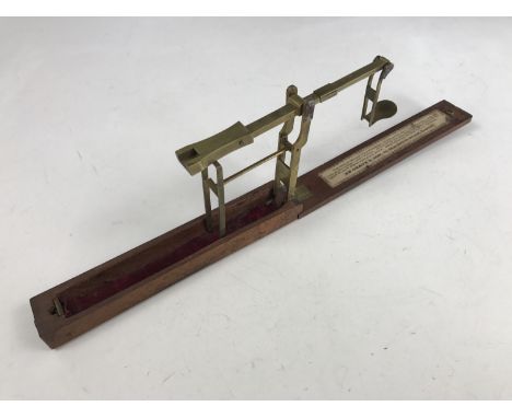 A Georgian set of pocket Sovereign scales, of brass cantilever construction, folding into a mahogany case, bearing printed pa