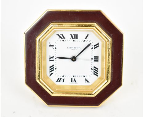 A Cartier manual wind, gilt brass and burgundy enamel travel clock having a white enamel dial with Roman numerals and centre 
