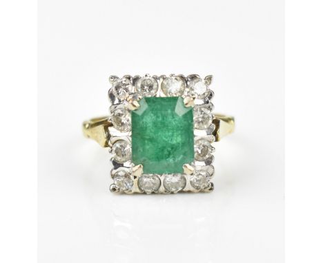 An 18ct yellow gold, emerald and diamond dress ring, with central step cut emerald in a halo of twelve brilliant cut diamonds