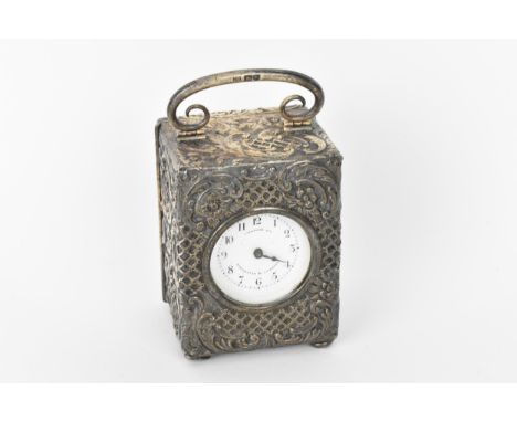 An early 20th century silver cased carriage clock, the embossed case decorated with C scrolls and stylised floral decoration,