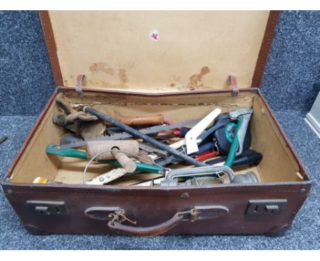 A vintage leather suitcase filled with old hand tools including folding military spade