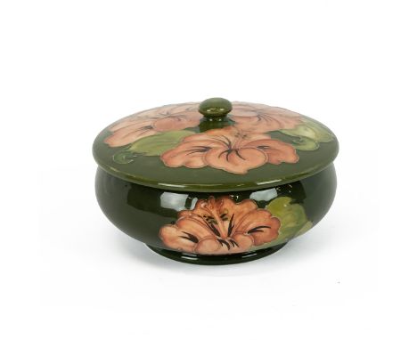 Walter Moorcroft mid 20th Century lidded bowl, the green ground with tube lined decoration of hibiscus flowers in salmon pink