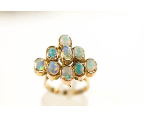 A nine stone opal ring, stamped '375', the oval shallow cabochons in a stepped arrangement, finger size N, 5.6 g gross