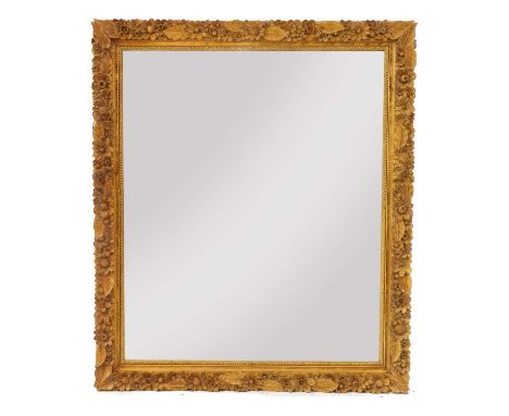 A large carved softwood wall mirror,of recent manufacture, the frame decorated with flowers and foliage surrounding a bevelle