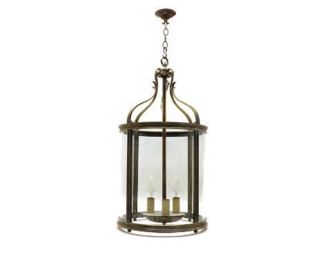 A Regency-style brass hall lantern,20th century, of cylindrical form, set with foliate scrolls above four glass panels, housi