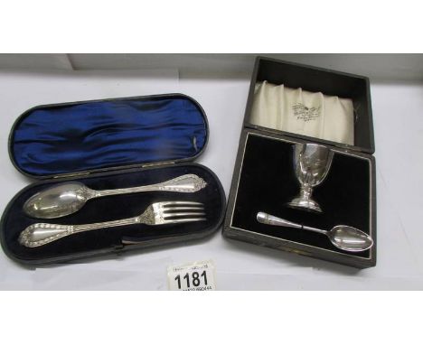 A cased silver christening egg cup with spoons and a cased silver spoon and fork set.