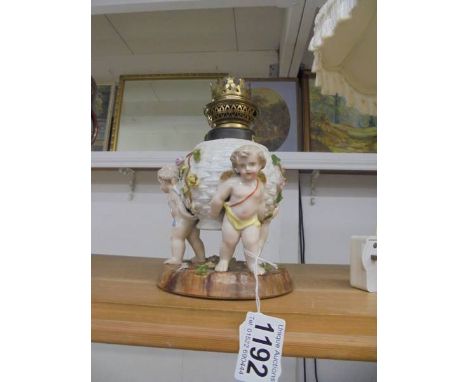 A 19th century cherub oil lamp.Small chipping to flower leaves & petals in places.Damage/loss to side of brass collar, approx