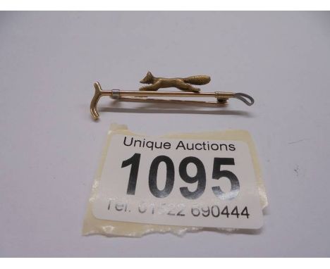 A 15ct gold stamped cravat pin of a gold textured fox on a riding crop, 4.6 grams.