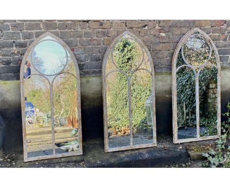 ARCHITECTURAL GARDEN MIRRORS, a set of three, Gothic style, aged metal frames, 122cm x 56cm. (3) 