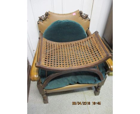 A low mahogany armchair with carved decoration in the form of two men playing an instrument, together with a cane stool 