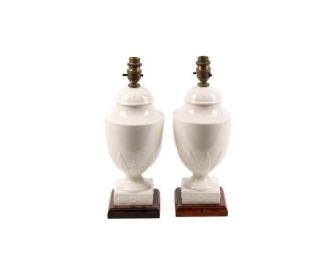 A pair of contemporary cream glazed ceramic table lamps. Of urn form raised on a moulded square wooden base. H27cm