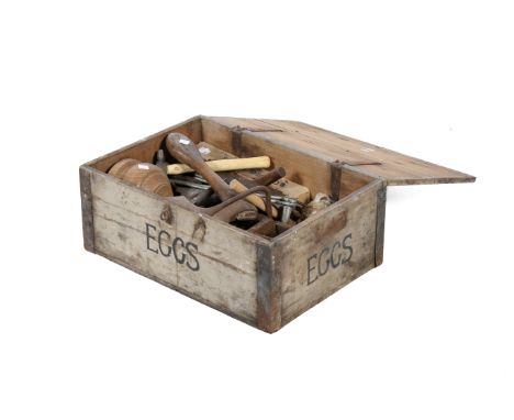 A collection of assorted vintage hand tools. Including tools used by a farrier and a small anvil, etc. In an old wooden ammo 