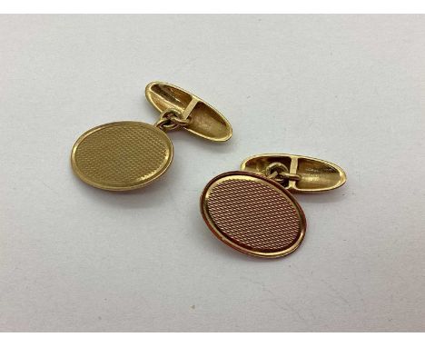 A Pair of 9ct Gold Cufflinks, each oval panel with engine turned decoration, on chain connections (6.5grams).