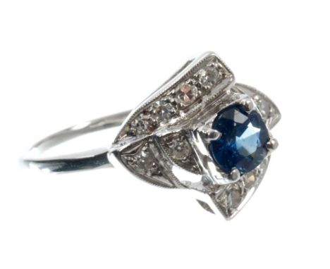 Art Deco sapphire and diamond cluster ring with a circular mixed cut blue sapphire in a stepped crossover design, with single