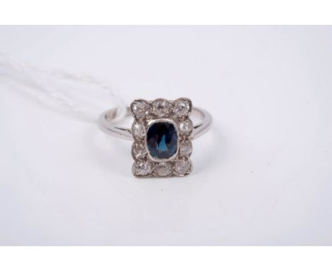 Sapphire and diamond cluster ring with an oval mixed cut blue sapphire surrounded by ten old cut diamonds with pierced galler