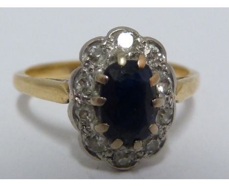 A diamond and sapphire ring, the oval sapphire approx 6mm max, encircled by 10 diamond chips set on a yellow gold band stampe