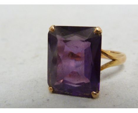 A 14ct yellow gold and amethyst ring, the rectangular stone claw set within a dentil pierced setting on bifurcated shank, mar