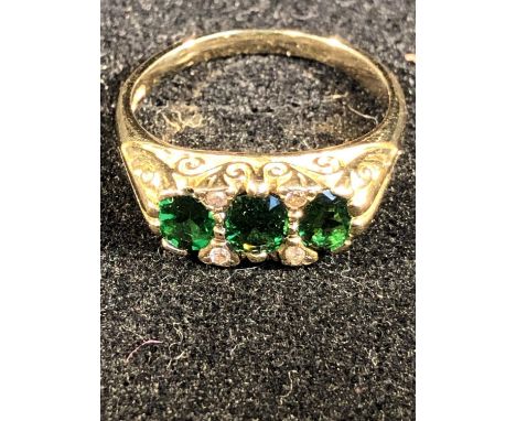 An emerald green tourmaline and diamond ring, the three stones  of graduated oval shape interspersed with four round diamonds