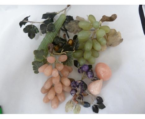 A group of hardstone fruit and vegetables, mostly grapes and leaves; in rose quartz, jade, amethyst, tigers eye coloured ston