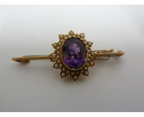 An amethyst and seed pearl bar brooch, the oval purple stone set in seed pearls in a star form in yellow metal, base metal pi