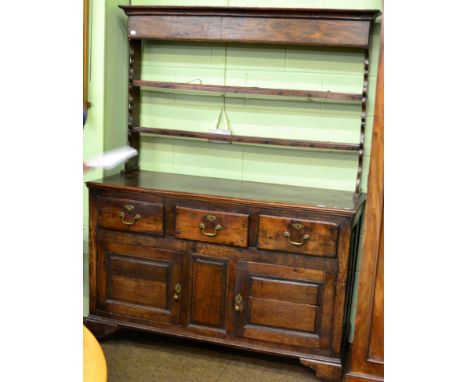 An 18th century oak enclosed dresser and rack, with two shelves and shaped end supports, the base with three deep drawers abo