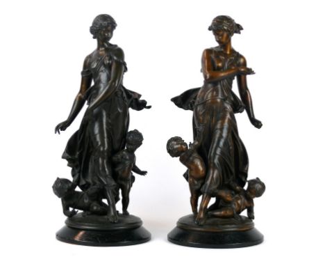 A pair of bronzed spelter figure groups
'Dumaige' each modelled as a woman wearing traditional clothing with two children pla