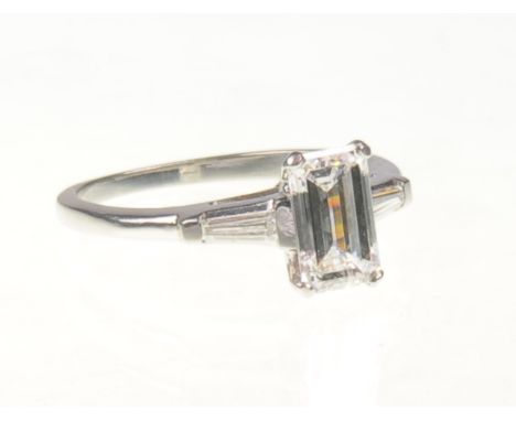 A platinum single stone emerald cut diamond ring, approx 1.58ct
The principal diamond flanked to the shoulders with two taper