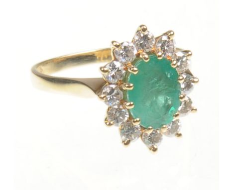 An 18ct yellow gold diamond and emerald cluster ring
The central facet cut oval emerald approx 10mm long, surrounded by twelv