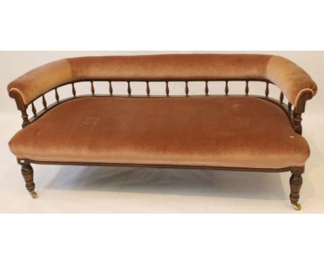 An elegant Victorian walnut framed low sofa
The curved upholstered top rail raised on spindle uprights, and fronted by carved