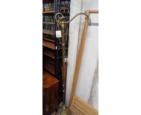 A vintage brass standard lamp with scroll top and plain pillar, set on an ornate cast trefoil base