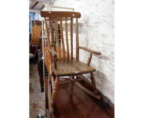 A vintage mixed wood lathe back rocking chair with solid moulded seat, set on turned supports
