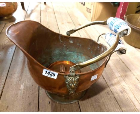 A vintage copper coal scuttle of helmet form with blue painted ceramic candles