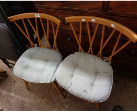 A pair of Ercol light elm 'Candlestick' kitchen chairs with moulded solid seats. set on simple turned supports