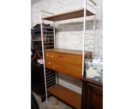 A vintage Ladderax single modular shelving unit comprising two white painted metal uprights, a fall-front cabinet and two she