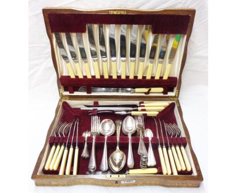 A vintage polished oak canteen containing a six place setting of ivorine handled silver plated  cutlery and a few spares
