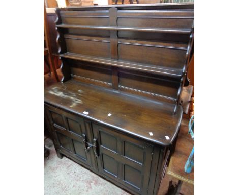 A 1.2m vintage Ercol dark elm two part dresser with two shelf open plate rack over a base with part fitted interior enclosed 