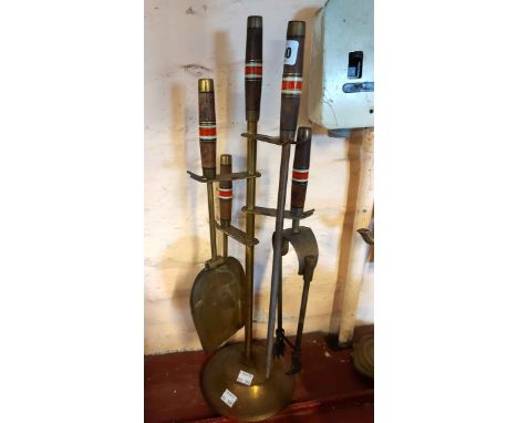 A vintage brass companion set, the wooden handles with coloured plastic and metal banded decoration comprising shovel, tongs,
