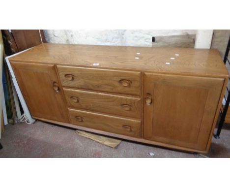 A 1.55m vintage Ercol 'Windsor' light elm sideboard with three central drawers and flanking cupboards, set on Shepherd caster